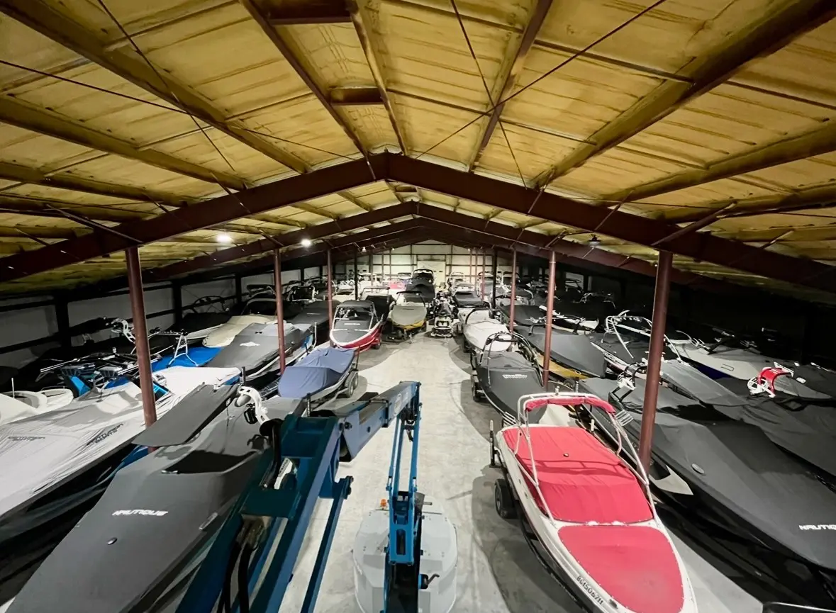 A large indoor boat storage facility filled with various boats.