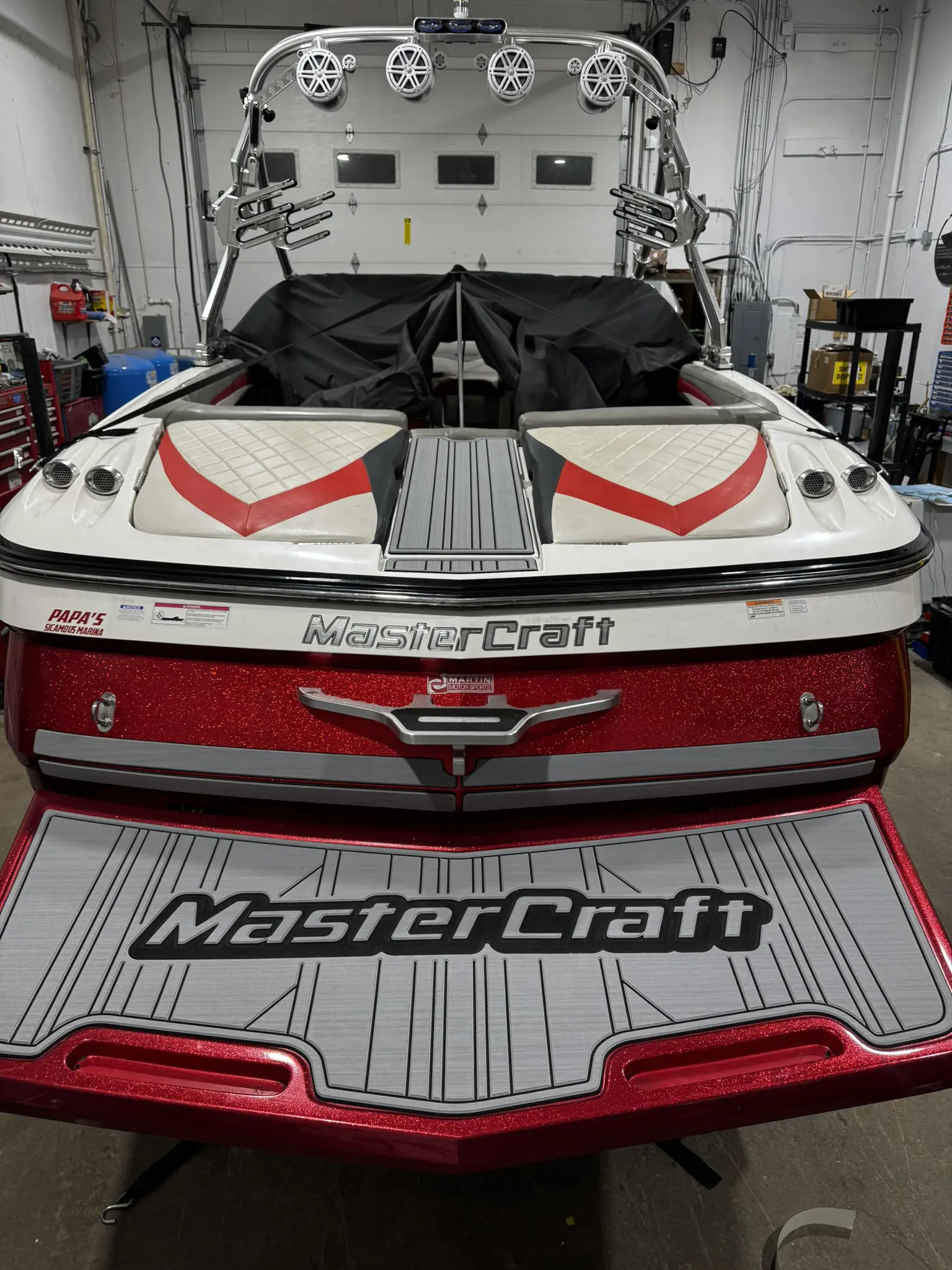Red and white MasterCraft boat in garage.