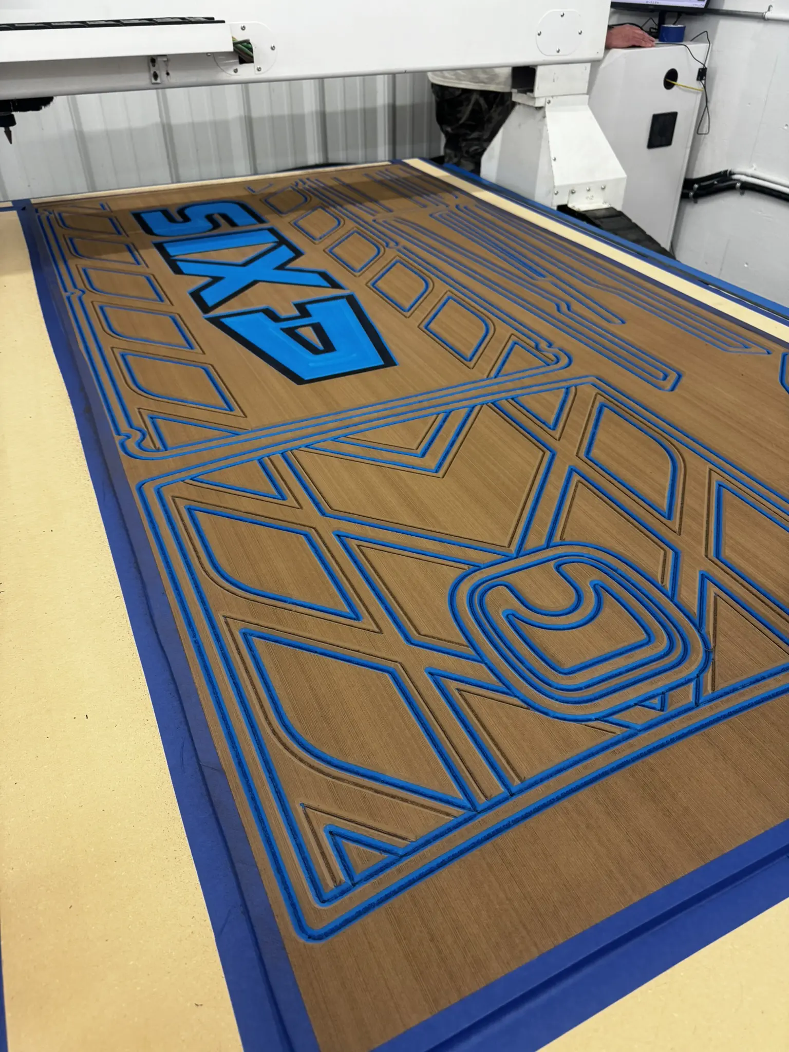 Machine carving intricate blue design on wood.