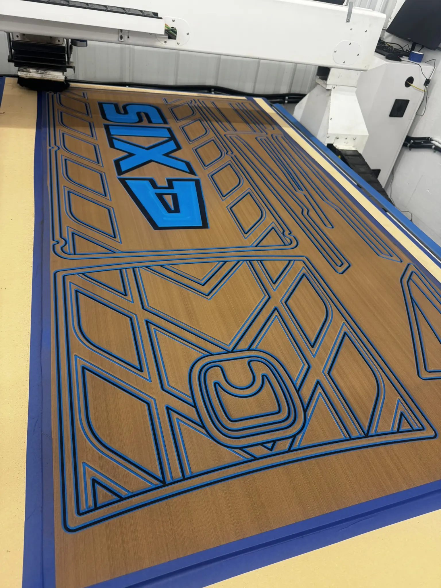 Wood engraving machine with geometric blue patterns.