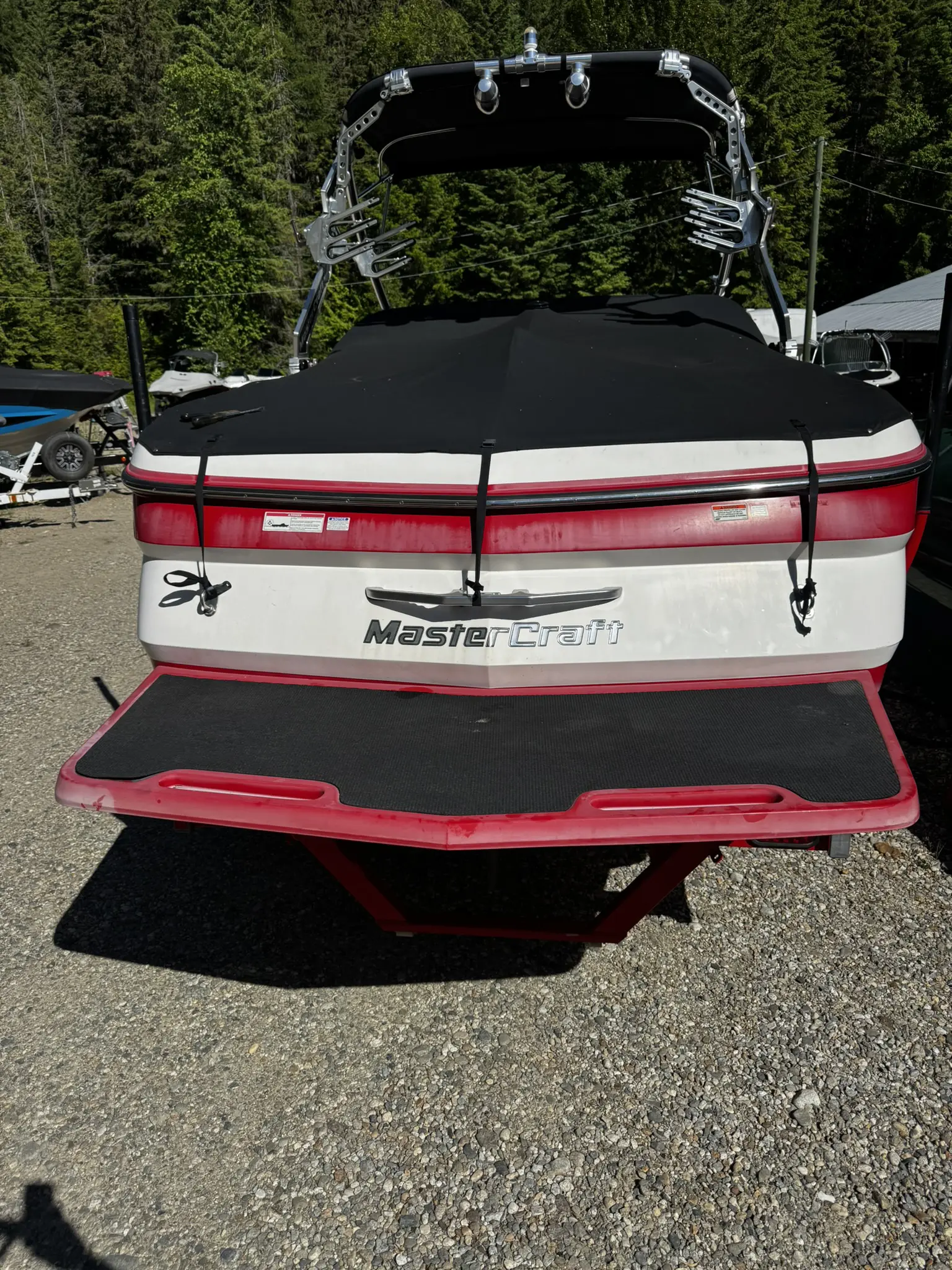 Red and white boat on gravel surface.